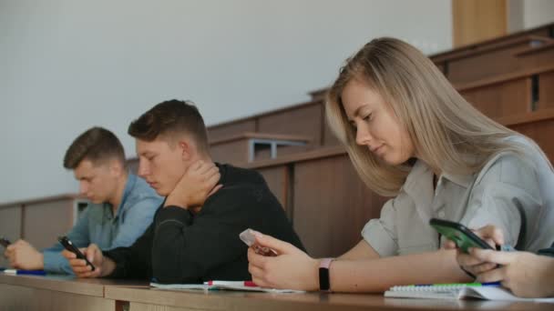 Nudny wykład na Uniwersytecie, uczniowie patrzą na ekrany smartfonów. Wiele osób — Wideo stockowe