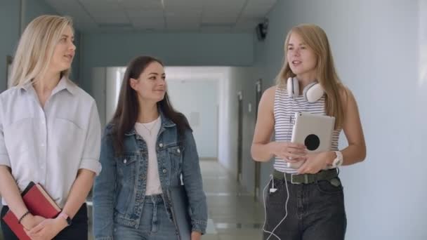 Tre giovani ragazze camminano lungo il corridoio e comunicano — Video Stock