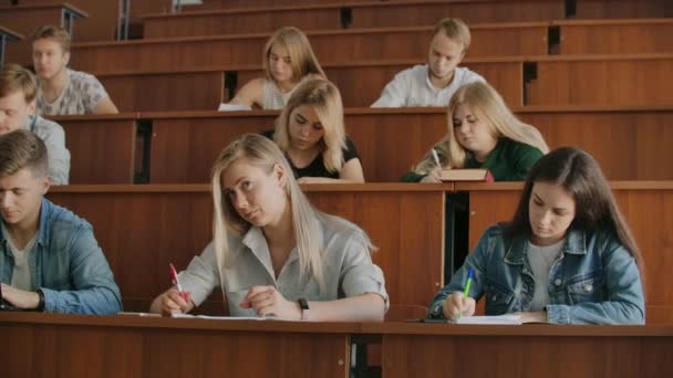 Jonge succesvolle studenten in een grote universitaire klas luisteren en nemen een lezing op, een echte lezing aan de Universiteit — Stockvideo