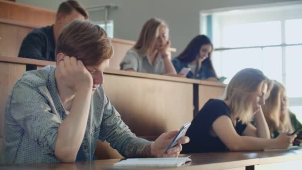 A boring lecture at the university, students look at the screens of smartphones. Many people — Stock Video