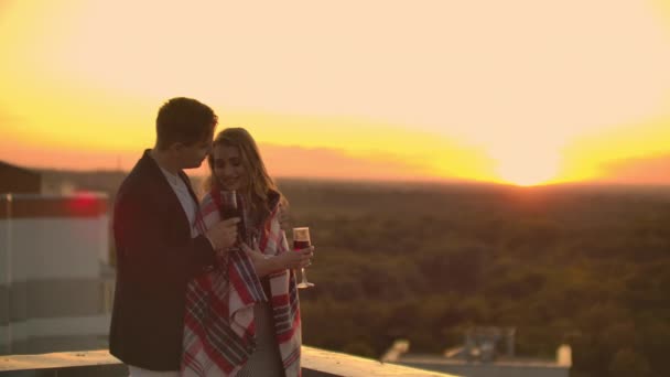 La pareja amorosa está sentada en el techo de la casa. En la distancia, las luces de la ciudad nocturna — Vídeos de Stock