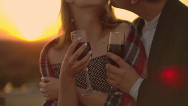 Närbild på händerna på kvinnor som innehar rött vinglas på balkongen under solnedgången, firande koncept. — Stockvideo
