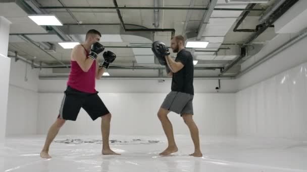 Boxer mužského bojovníka s trenéry cvičí techniku ran a uhýbal údery v pomalém pohybu. Příprava na zápas s trenérem. Profesionální bojovník. — Stock video