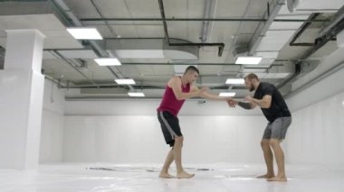 Erkek güreşçilerden sonra kamera hareket eder. Mma dövüşçüleri antrenman pistlerinde güreş ekipmanları üzerinde çalışırlar. Yakalama, atar ve acı hamle