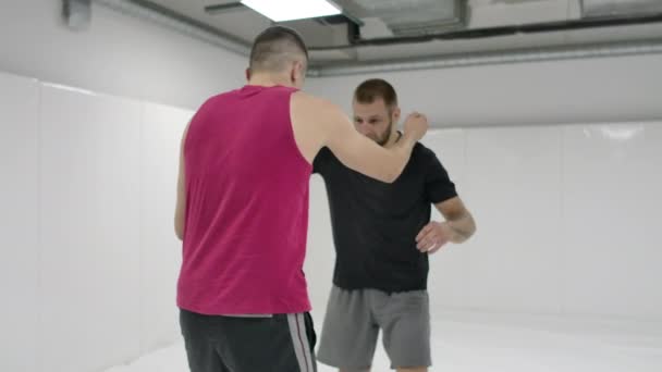 希腊罗马摔跤手在一间带垫子的白色房间里。练习自卫技巧。投掷和疼痛 — 图库视频影像