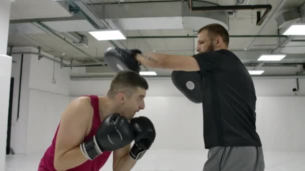 Boxer mužského bojovníka s trenéry cvičí techniku ran a uhýbal údery v pomalém pohybu. Příprava na zápas s trenérem. Profesionální bojovník. — Stock video