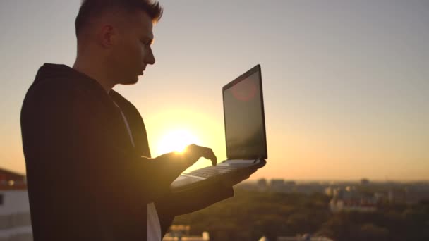 Hacker använder laptop på taket med utsikt över staden och Forex diagram. Hacking och stats Concept — Stockvideo