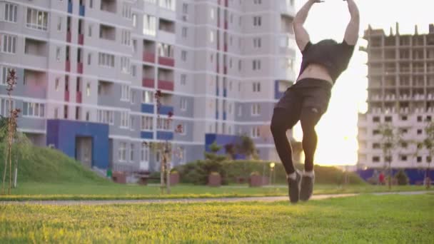 Ένας αθλητής που κάνει ακραία ώθηση στον Σούπερμαν χρησιμοποιώντας πισωγίξεις και κάμψεις στο ηλιοβασίλεμα σε αργή motionon φόντο της πόλης — Αρχείο Βίντεο