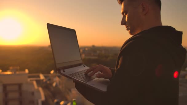 Хакер використовує ноутбук на даху з видом на місто та графіком валют. Концепція злому та статистики — стокове відео
