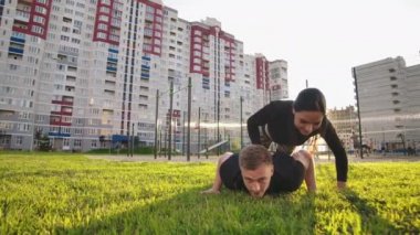 Adam ve kız şınav ları dışarıda. Erkek ve kadın birlikte açık havada egzersiz yapıyor. Çift gerginlik içinde vücut tutarak spor yapıyor, uzatılmış kollar eğilerek.