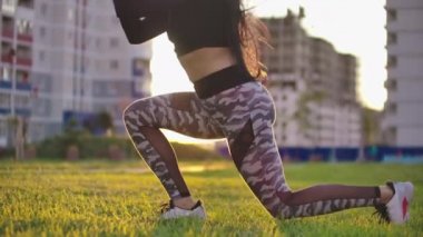 genç fit ve enerjik kadın gün batımı nda şehir parkında sağlıklı yaşam tarzı için ağırlıkları ile spor egzersiz ve fitness lunge egzersizleri yapıyor.