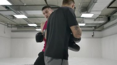 Antrenör ve boksör atlama vuruşunu yavaş çekimde yapıyor. Kickboks antrenmanı