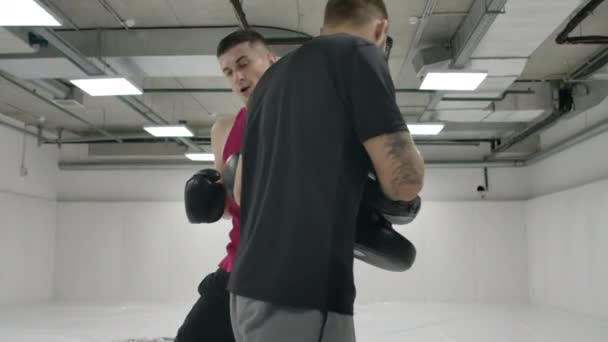 El entrenador y el luchador trabajan la patada en la rodilla de salto en las patas en cámara lenta. Entrenamiento para kickboxing — Vídeos de Stock