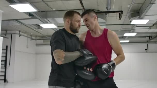 Lors de l'entraînement sur les combats mixtes, l'homme bat un genou sur les pattes de l'entraîneur dans un saut. Mouvement lent — Video