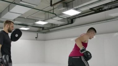 Adam boks patisini tekmeliyor. Eğitmenle dövüş tekniği uyguluyor.