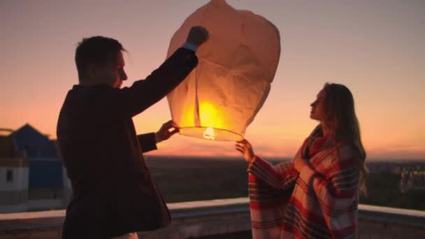 To launch a sky lantern at night on the roof. The lovers are together. Chinese sky lanterns — Stock Video