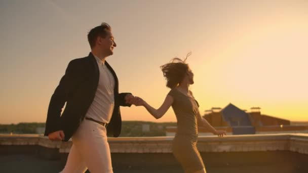 Чоловік з жінкою, що біжить на даху, тримається за руки. Повільні коханці руху на даху — стокове відео