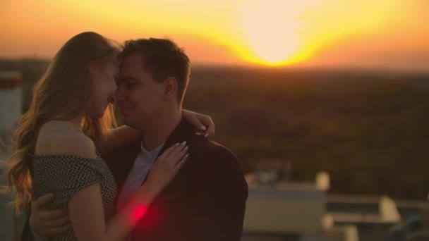 Abrazándose de pie en el techo al atardecer. Techo de verano al atardecer. Un hombre con una chica vino en una cita romántica en el techo — Vídeos de Stock