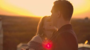 Gün batımında gün batımında iki aşık çatıda dans eder.