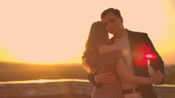 Dois amantes dançam juntos no telhado ao pôr do sol à luz do sol — Vídeo de Stock