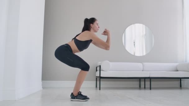 Femme brune mince effectue une série de squats à la maison au ralenti — Video