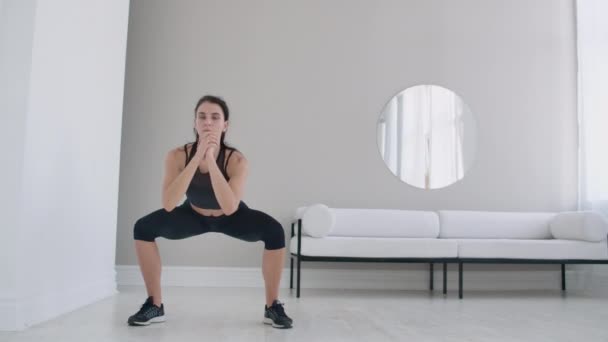 Snella donna bruna esegue una serie di squat a casa al rallentatore — Video Stock