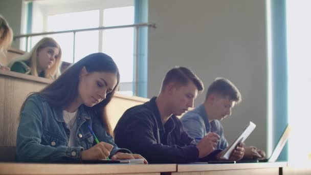 Πανεπιστημιακή παραγωγή ένα μεγάλο ακροατήριο, φοιτητές γράφουν στα σημειωματάρια διάλεξη και φορητούς υπολογιστές — Αρχείο Βίντεο