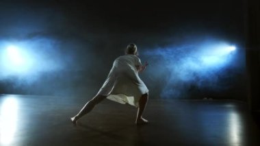 Modern bale dansçısı kadın çıplak ayakla döner, döner ve dans adımları atar sahnede ağır çekimde dumanla durur. Sahnede performans