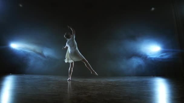 Mujer bailando ballet moderno descalza haciendo giros y piruetas y pasos de baile de pie en el escenario en el humo en cámara lenta. Rendimiento en el escenario — Vídeo de stock