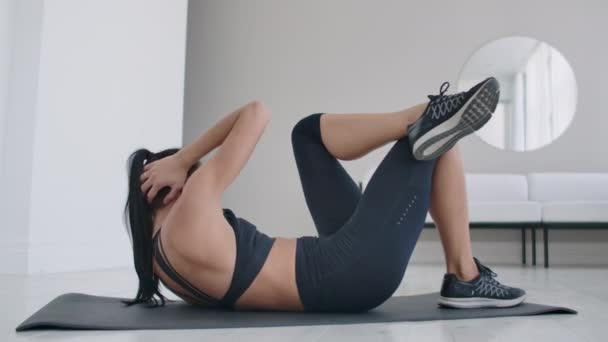 白人黑发女人躺在地毯上做腹肌运动。 为健康的身体每天在家里锻炼 — 图库视频影像