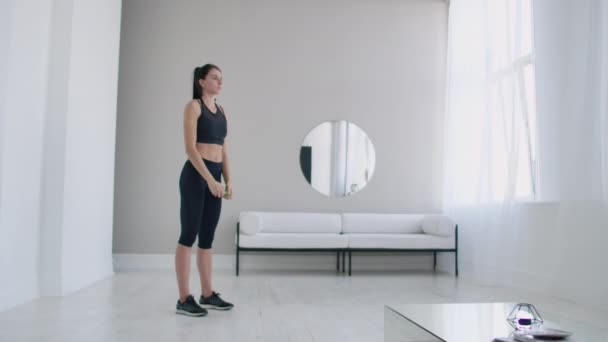 Brunette femelle fait échauffement et des exercices dans son appartement le matin, tourne le corps aveuglément et à droite avec les bras redressés — Video