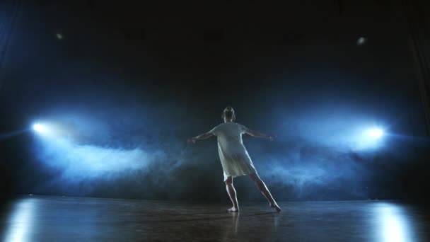 Modern ballet dancing woman barefoot doing spins and pirouettes and dance steps standing on stage in smoke in slow motion. Performance on stage — Stock Video