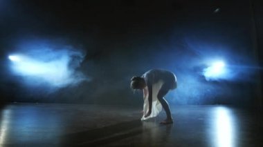 Modern bale dansçısı kadın yalın ayak yerde yatıyor ve dönüş yapıyor ve takla atıyor.