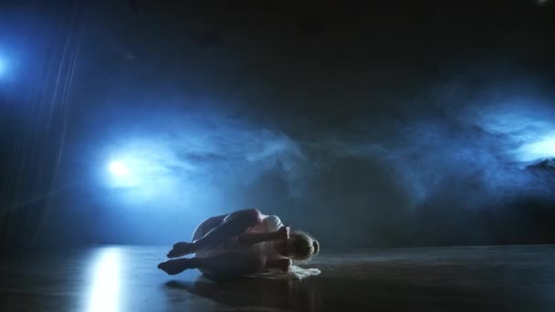 Современная балетная танцовщица босиком лежит на полу, вертя спинами, пируэтами и сальто. — стоковое видео