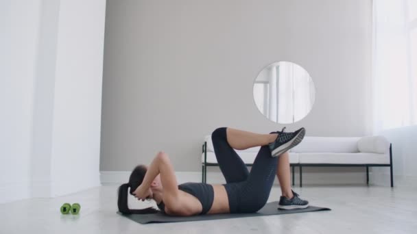 Brünette führt Bauchmuskelgymnastik auf dem Boden liegend aus und hebt ihren Körper auf die Knie — Stockvideo