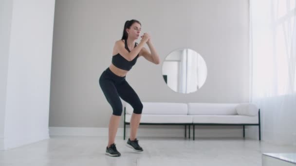 Femme brune mince effectue une série de squats à la maison au ralenti — Video