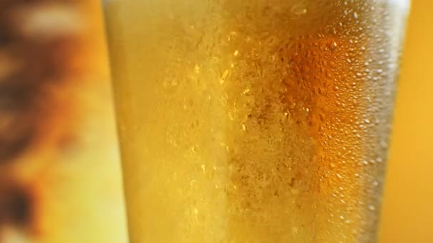 Ölen hälls i vinklat glas. IPA på språng. Cold Light Beer i ett glas med vattendroppar. Hantverksöl bildar vågor på nära håll. Fräschhet och skum. Bar bakgrund. Mikrobryggeriöl — Stockvideo