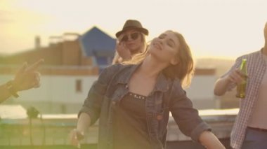 Dancing girl rooftop party slow motion group of multiracial friends hanging out young asian woman dancing enjoying roof top event at sunset drinking alcohol having fun on weekend celebration.