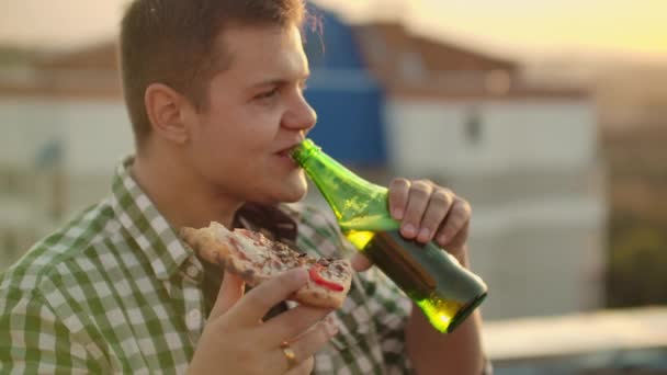 Jongen drinkt bier en eet pizza op het feest. — Stockvideo