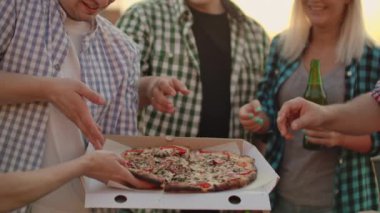 Altı gençten oluşan bir şirket birlikte pizza yiyor.