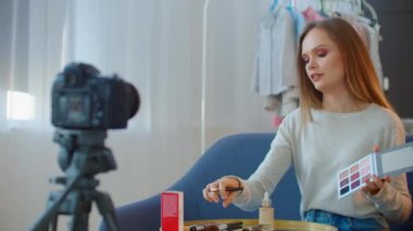 Genç ve güzel bir kadın profesyonel güzellik blogcusu veya blog yazarı sosyal medyada paylaşmak için makyaj yapıyor..