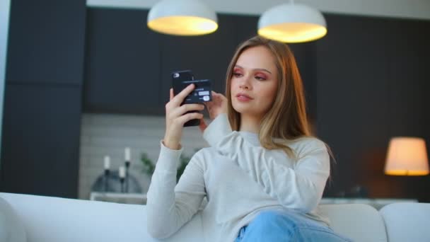 Belle femme en ligne bancaire en utilisant smartphone shopping en ligne avec carte de crédit à la maison style de vie. — Video