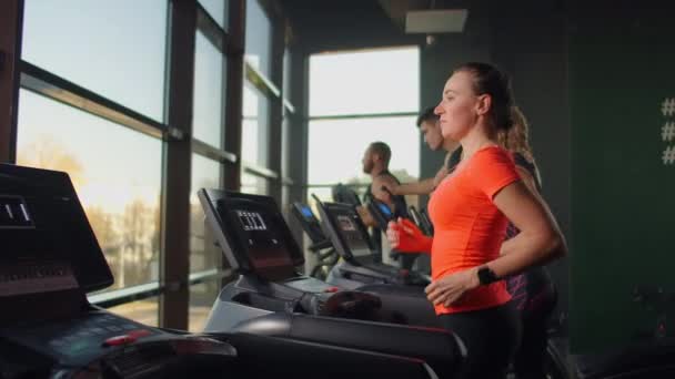 Spor salonundaki panoramik pencerelerin önünde koşu bandında koşan tatlı genç kız. Koşu bandı ve geniş pencereli spor salonu — Stok video