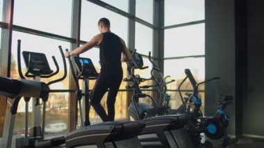 Spor salonunda eliptik çapraz antrenör eğitimi almadan önce portre fitness adamı ısınıyor. Spor salonunda çapraz antrenör üzerine yakın çekim erkek kardiyo egzersizi..