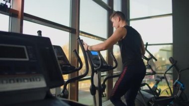 Spor salonunda eliptik çapraz antrenör eğitimi almadan önce portre fitness adamı ısınıyor. Spor salonunda çapraz antrenör üzerine yakın çekim erkek kardiyo egzersizi..