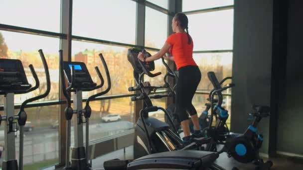 Jolie jeune brune faisant des exercices de cuisse sur le simulateur. Simulateurs modernes près de la fenêtre panoramique — Video