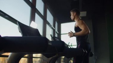 Spor salonunda spor yapan ve koşu bandında yürüyen genç erkek ve kadınlar.