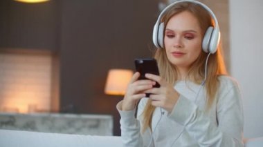 Genç mutlu kadın kanepede müzik dinliyor. Genç, mutlu, çekici bir kadın. Kanepede müzik dinliyor..