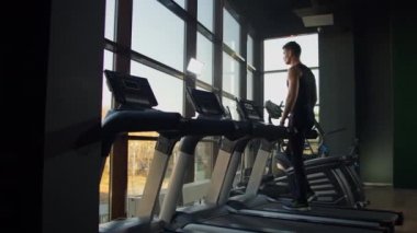 Spor salonunda spor yapan ve koşu bandında yürüyen genç erkek ve kadınlar..