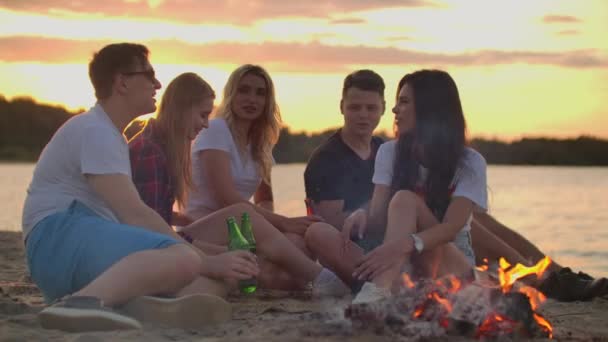 Los jóvenes disfrutan de una cálida velada de verano en la playa de arena — Vídeo de stock